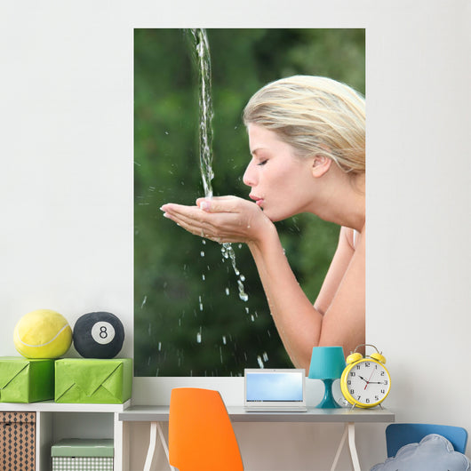 Blond woman drinking water from fountain Wall Mural