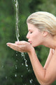 Blond woman drinking water from fountain Wall Mural