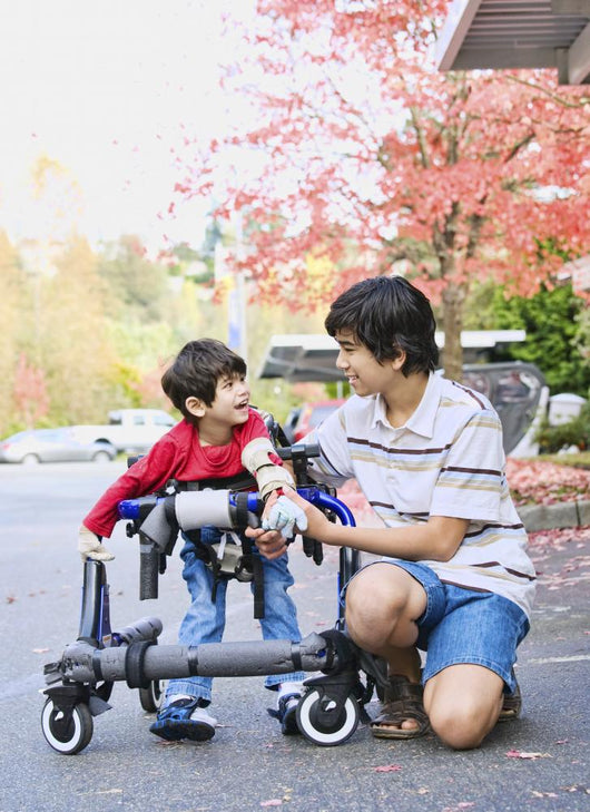 Teen boy with disabled little brother in walker Wall Mural