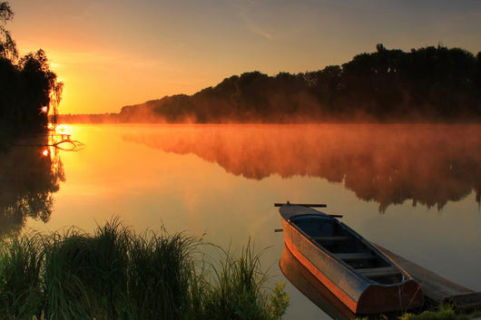 Boat on the shore of a misty lake Wall Mural