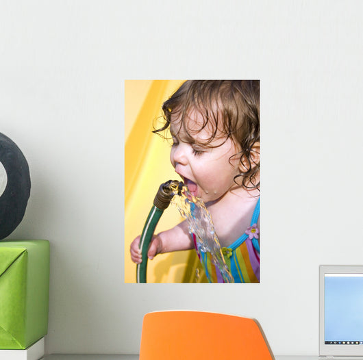 a toddler drinking water from a garden hose Wall Mural