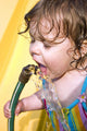 a toddler drinking water from a garden hose Wall Mural