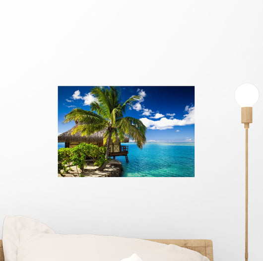 Tropical bungalow and palm tree next to amazing lagoon Wall Mural
