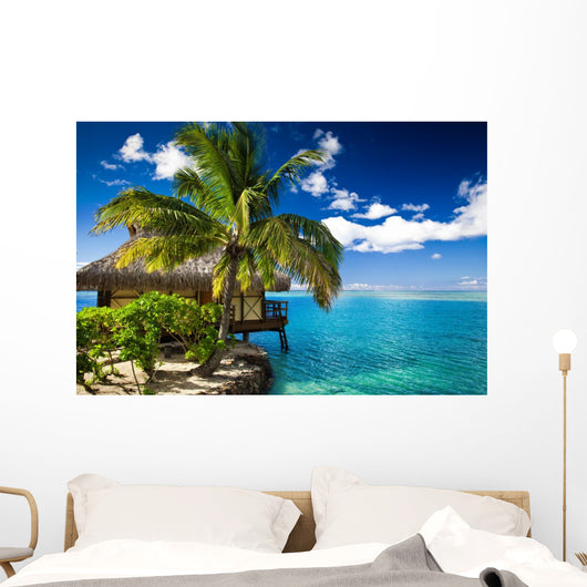 Tropical bungalow and palm tree next to amazing lagoon Wall Mural
