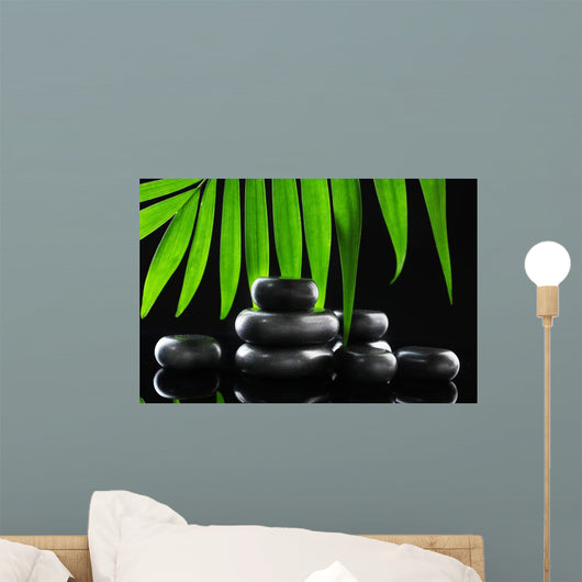 Spa stones and green palm leaf on black background Wall Mural