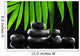 Spa stones and green palm leaf on black background Wall Mural