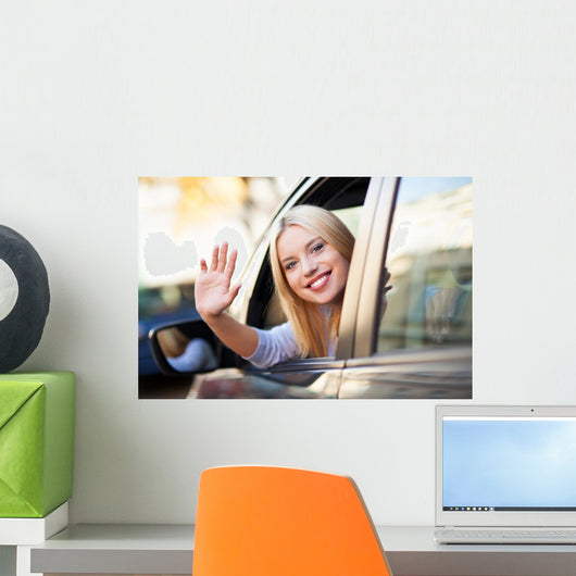 Young woman waving from car window Wall Mural
