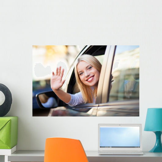 Young woman waving from car window Wall Mural
