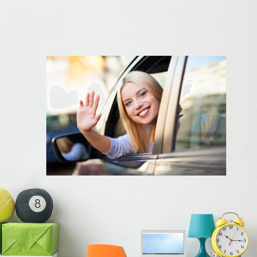 Young woman waving from car window Wall Mural