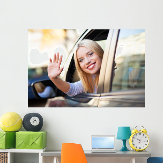 Young woman waving from car window Wall Mural