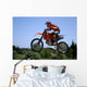 red and orange moto x or motor cross bike giving big air on dirt Wall Mural
