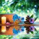 two candles and towels black stones and purple daisy on water Wall Mural