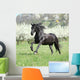 Gorgeous friesian mare running in front of flowering trees Wall Mural