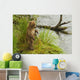 Brown bear cub standing in grass at edge of Brooks River in rain Wall Mural