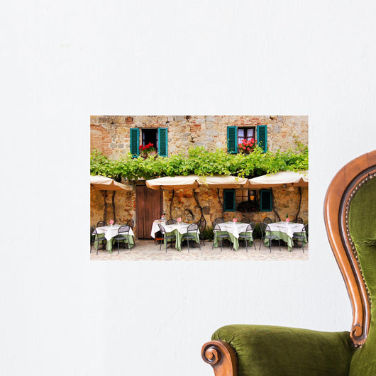 Cafe tables and chairs outside a stone building in Tuscany Wall Mural