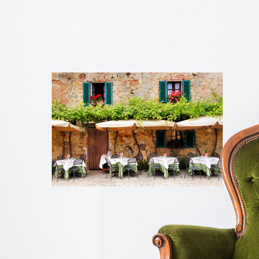 Cafe tables and chairs outside a stone building in Tuscany Wall Mural