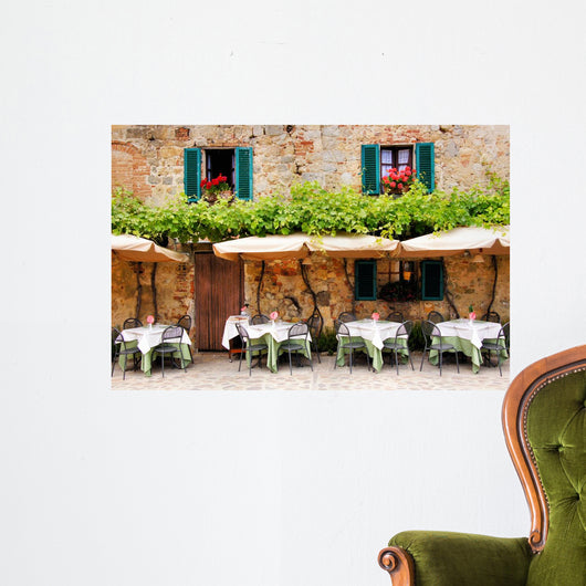 Cafe tables and chairs outside a stone building in Tuscany Wall Mural