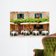 Cafe tables and chairs outside a stone building in Tuscany Wall Mural