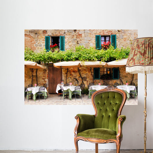 Cafe tables and chairs outside a stone building in Tuscany Wall Mural