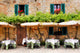Cafe tables and chairs outside a stone building in Tuscany Wall Mural