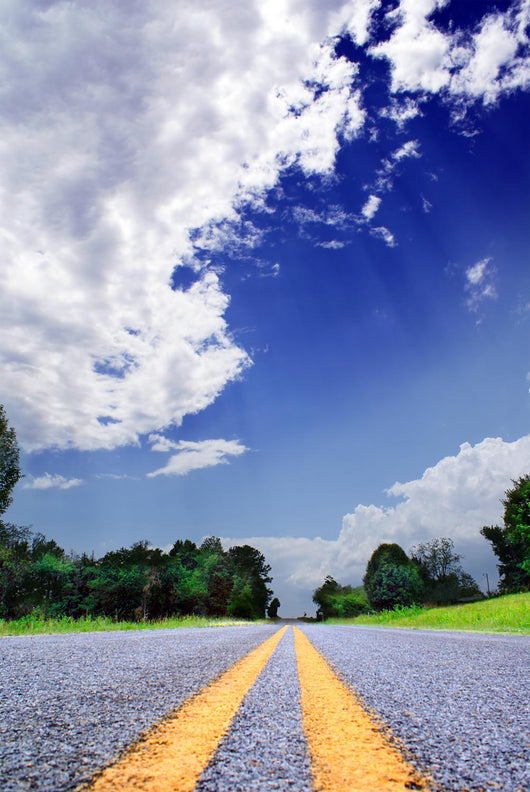Country-road under a dramatically lighted cloudy sky Wall Mural