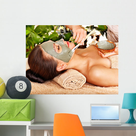 Woman having clay facial mask apply by beautician. 
