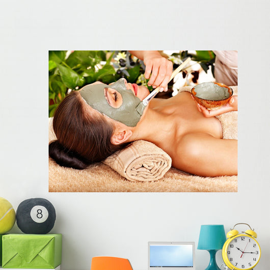 Woman having clay facial mask apply by beautician. 