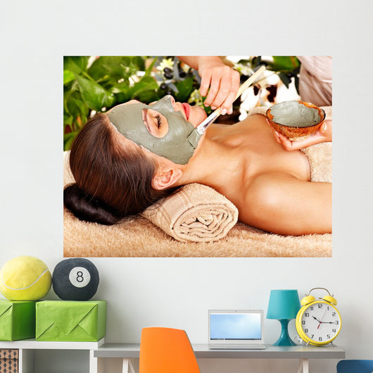 Woman having clay facial mask apply by beautician. 