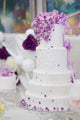White Wedding Cake Decorated With Purple Flowers 