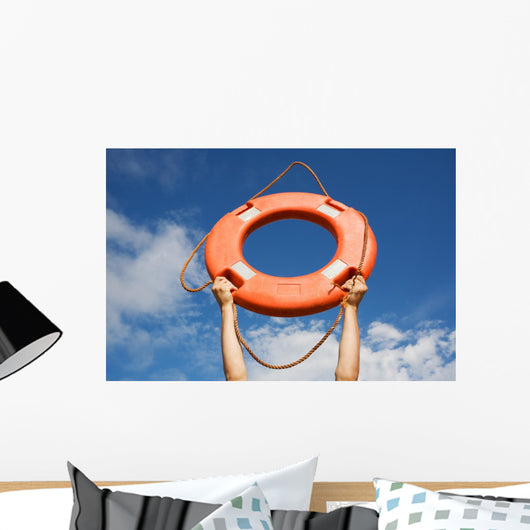 Life buoy ring in man's hands on a background of the sky. Wall Mural