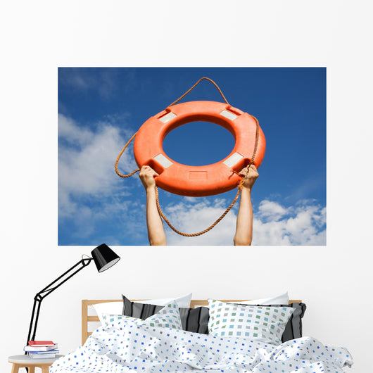 Life buoy ring in man's hands on a background of the sky. Wall Mural