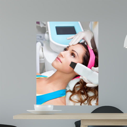 Woman getting laser face treatment in medical spa center 