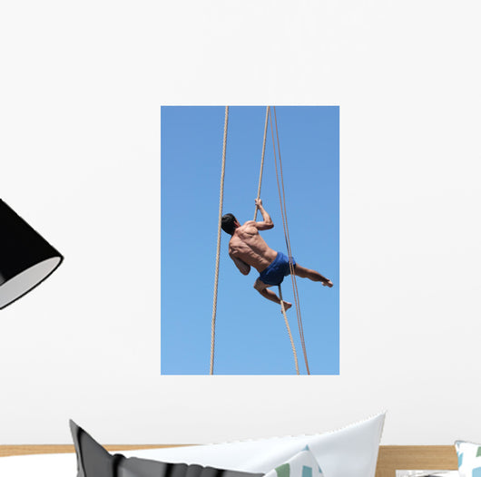 Shirtless athlete climbing up the rope Wall Mural