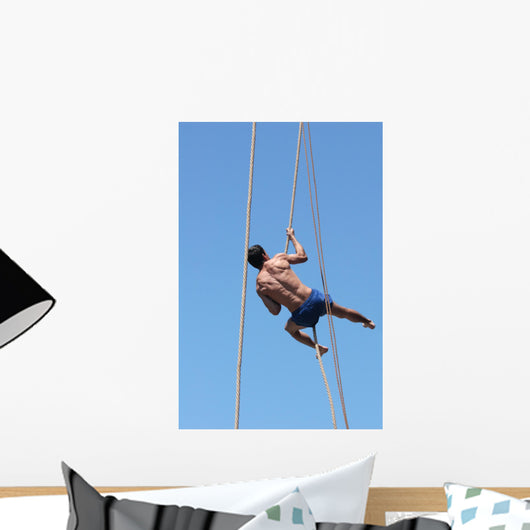 Shirtless athlete climbing up the rope Wall Mural