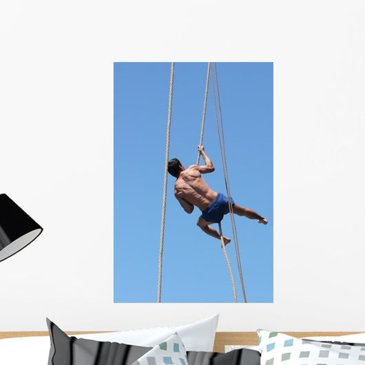 Shirtless athlete climbing up the rope Wall Mural