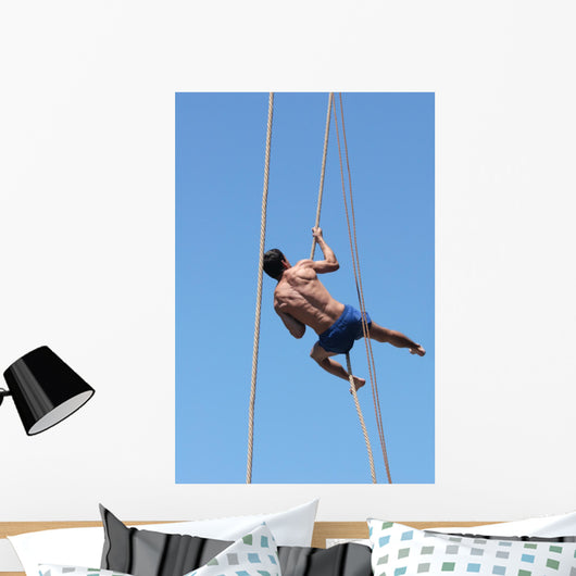 Shirtless athlete climbing up the rope Wall Mural