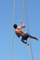 Shirtless athlete climbing up the rope Wall Mural