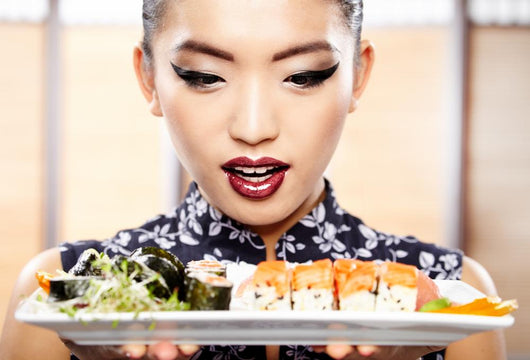 Beautiful young woman eating sushi. Shallow depth of field, focu 