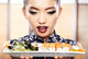 Beautiful young woman eating sushi. Shallow depth of field, focu 