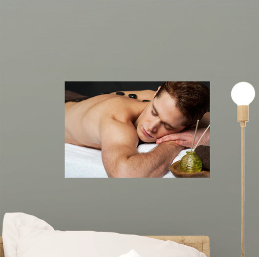 Man relaxing on a massage bed with hot stones Wall Mural