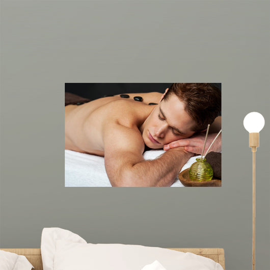 Man relaxing on a massage bed with hot stones Wall Mural