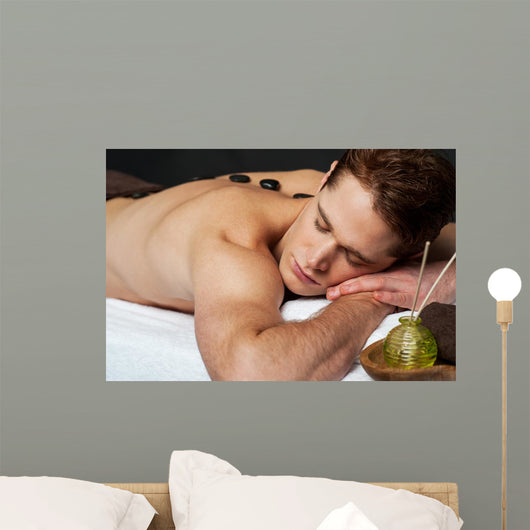 Man relaxing on a massage bed with hot stones Wall Mural