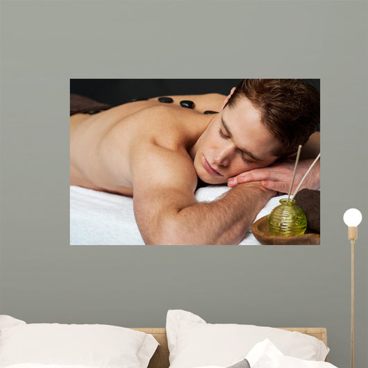 Man relaxing on a massage bed with hot stones Wall Mural