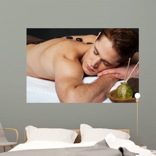 Man relaxing on a massage bed with hot stones Wall Mural