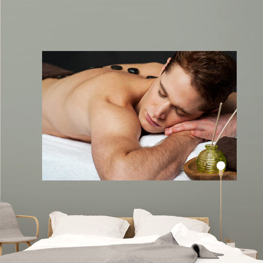 Man relaxing on a massage bed with hot stones Wall Mural