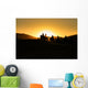 Silhouettes of tourists riding camels on dunes Wall Mural