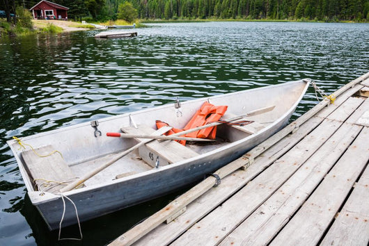 Old Row Boat  with Lifejackets Moored to Dock in Lake 