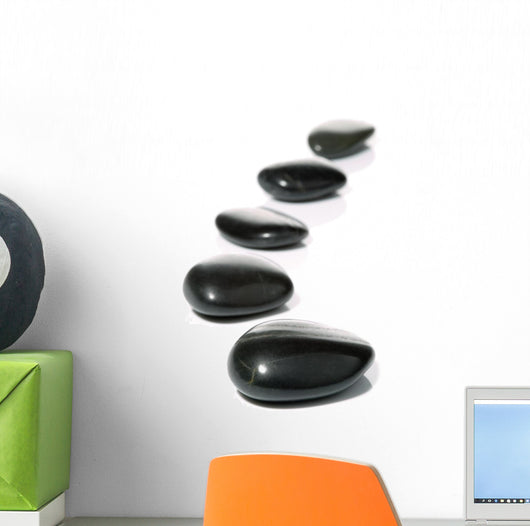 Five black pebbles in a gentle curve on a white surface Wall Mural