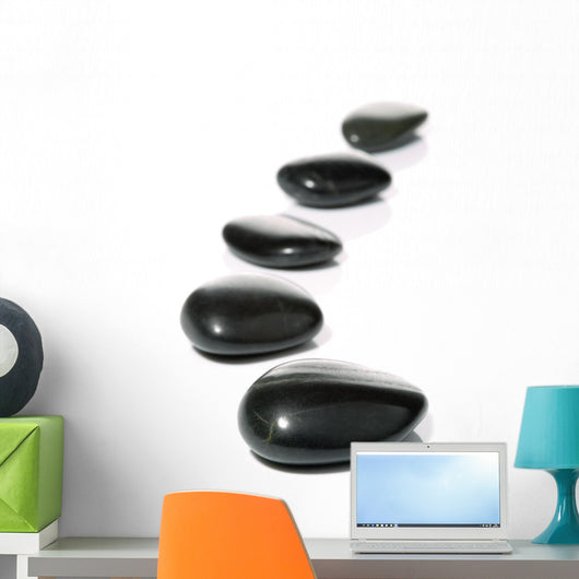 Five black pebbles in a gentle curve on a white surface Wall Mural
