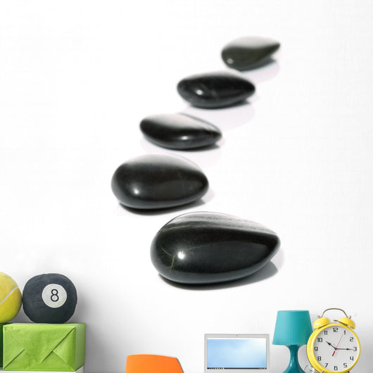 Five black pebbles in a gentle curve on a white surface Wall Mural